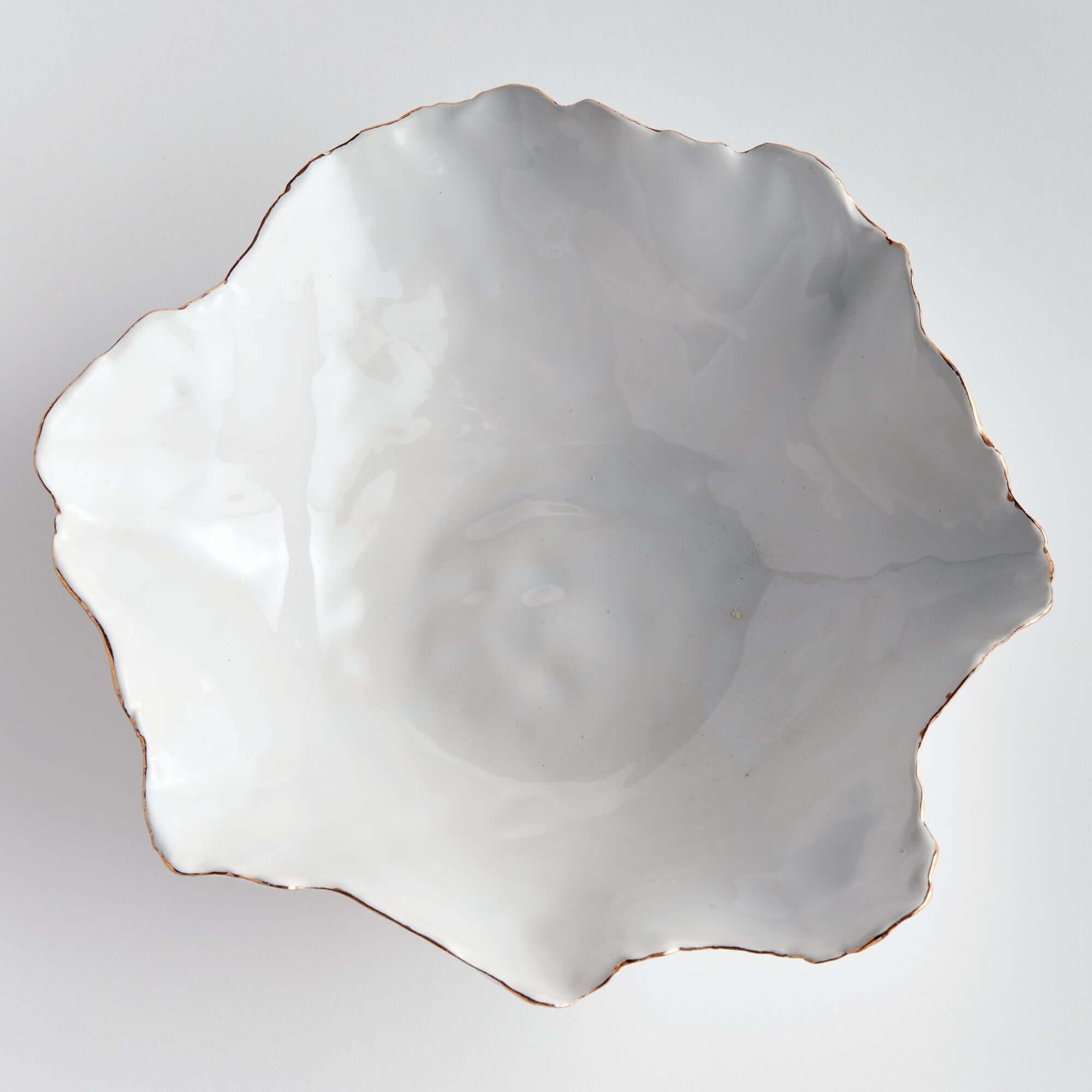White ceramic shell-shaped dish on a light gray background