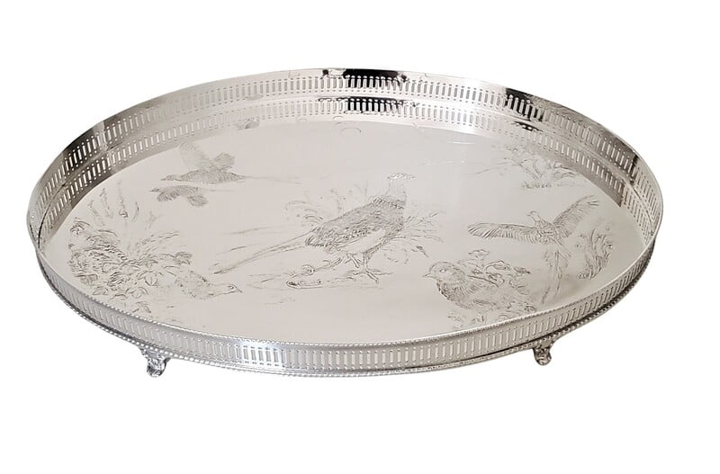 Decorative round silver tray with engraved designs on a white background
