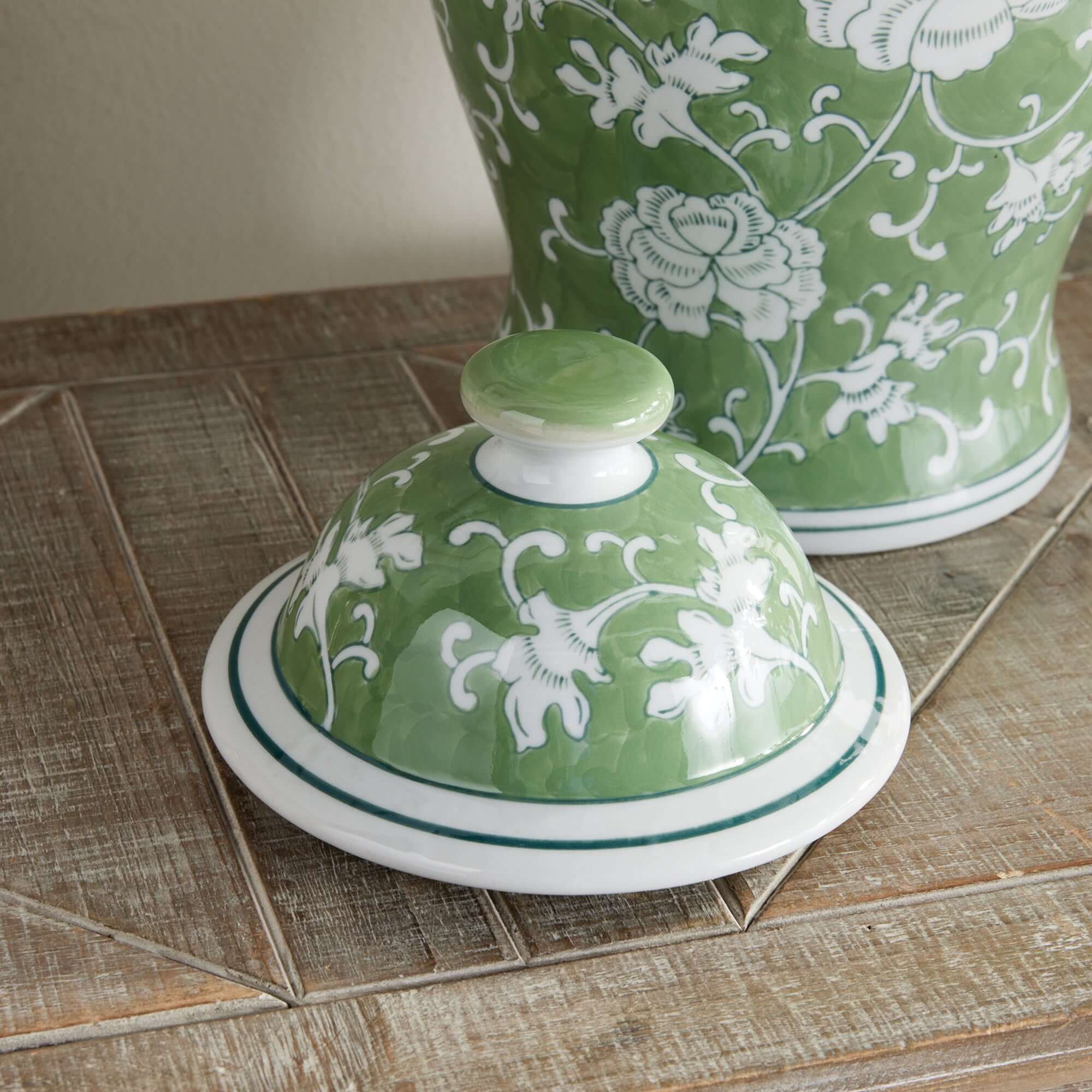 Green ceramic dish with white floral patterns on a wooden surface