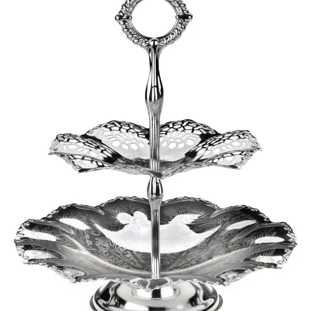 Silver two-tiered serving tray with intricate designs on a white background