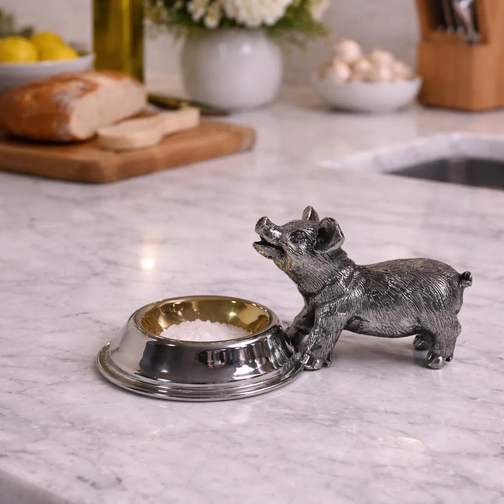Decorative silver plate salt cellar shaped like a pig on a kitchen counter.
