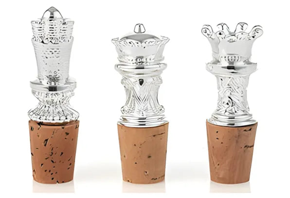Three silver bottle stoppers with cork bases on a white background